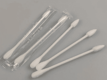 Several double-tipped cotton swabs, some still in packaging, on a gray surface