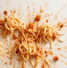 Spaghetti with red tomato sauce splattered across a pale surface